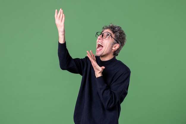 Portrait of genius man dressed casually in studio shot pointing above green wall