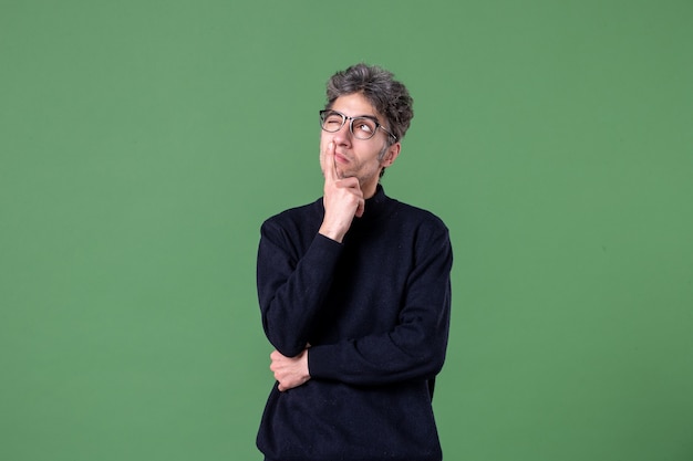 Portrait of genius man dressed casually in studio shot thinking green wall