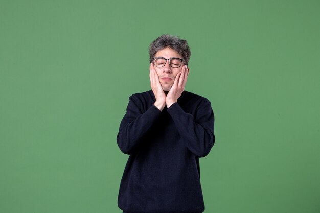 Portrait of genius man dressed casually in studio shot with closed eyes green wall