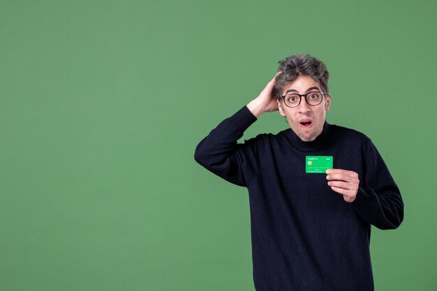 Portrait of genius man holding credit card in studio shot green wall