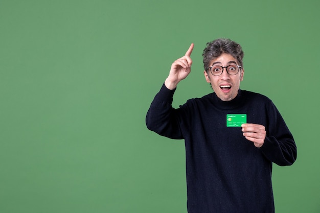 Free photo portrait of genius man holding credit card in studio shot green wall