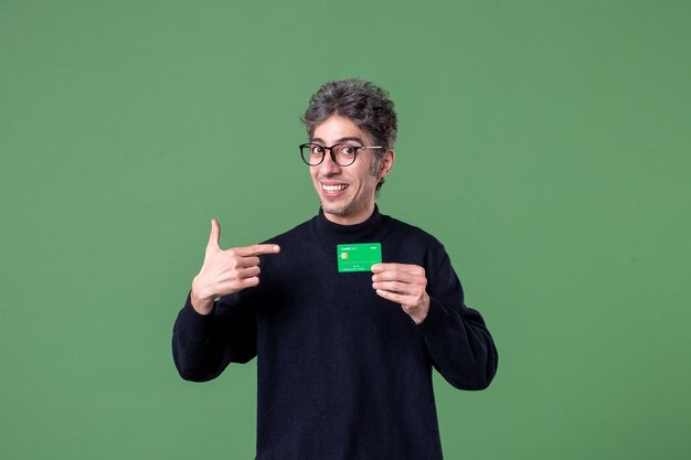 Portrait of genius man holding green credit card on green wall