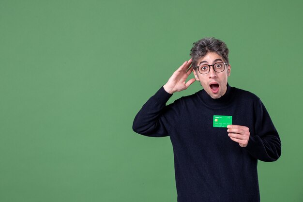 Portrait of genius man holding green credit card in studio shot green wall