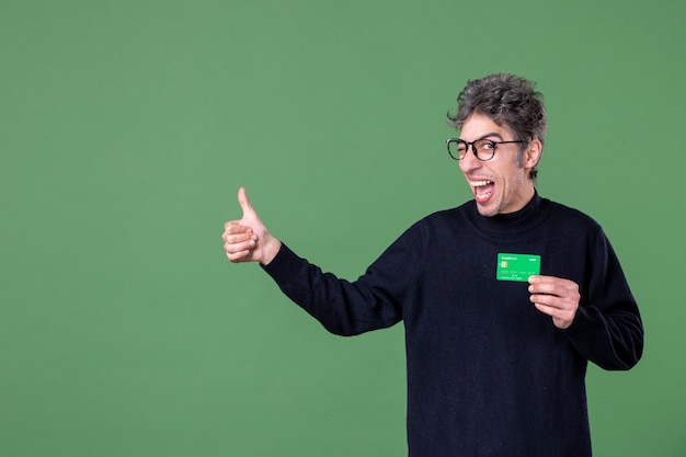 Portrait of genius man holding green credit card in studio shot green wall