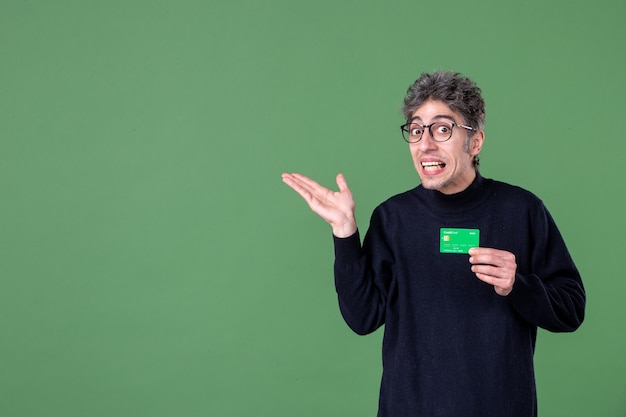 Портрет гениального человека, держащего зеленую кредитную карту в студии, выстрелил в зеленую стену