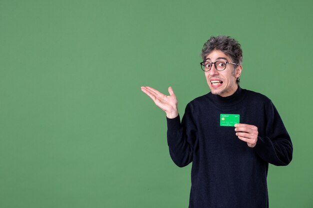 Portrait of genius man holding green credit card in studio shot green wall