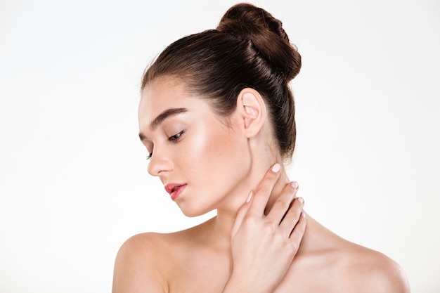 Portrait of gentle young woman with healthy body touching her neck posing with face downwards