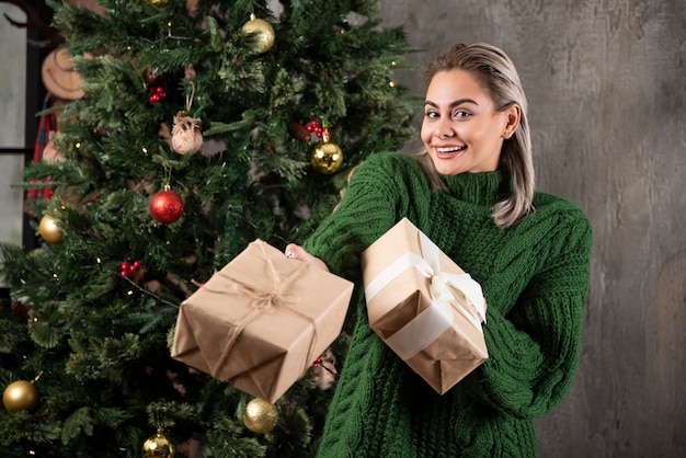 Портрет девушки, одетой в зеленый свитер, дарит рождественский подарок