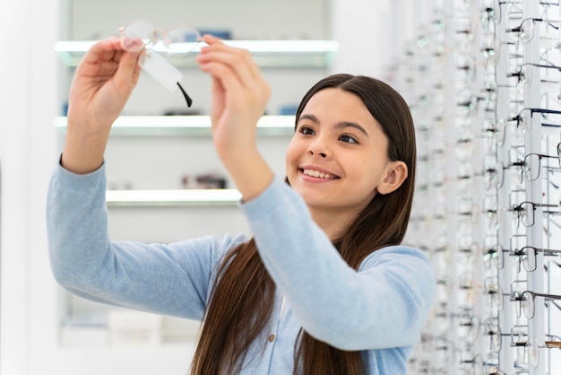 Portrait girl in eyeglasses store choosing pair