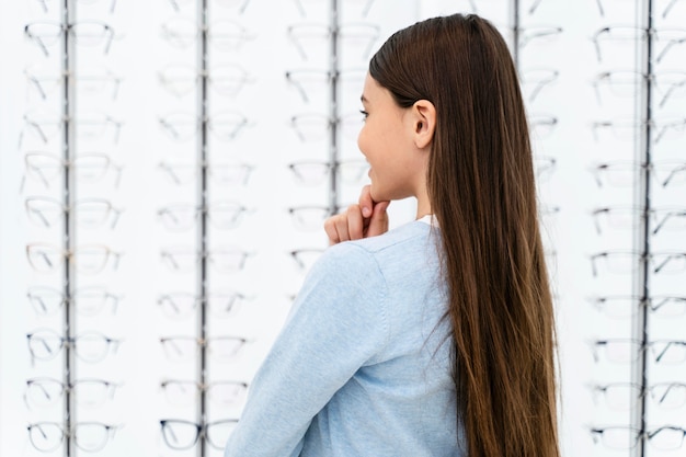 Portrait girl in eyeglasses store choosing pair