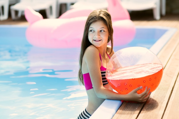 Portrait of girl holding a beach ball looking away