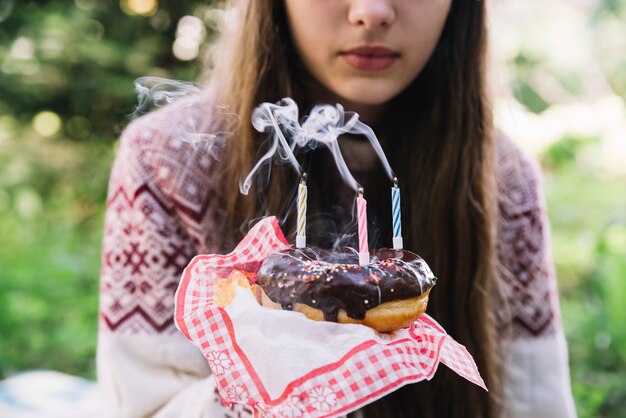 Portrait girl holding chocolate donut with extinguish candles