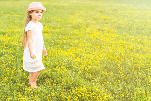 牧草地に手を立てて花を持っている少女の肖像