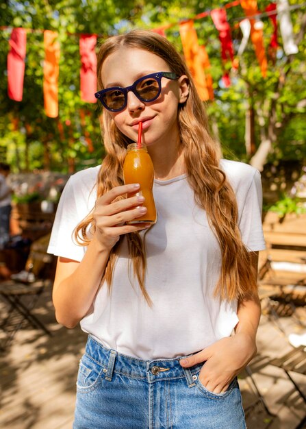 Free photo portrait of girl holding fresh juice bottle in park