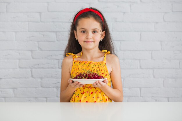 Portrait of a girl holding plate of red cherries