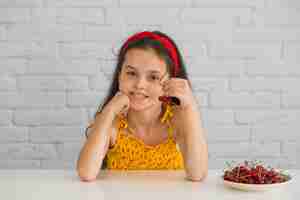 Free photo portrait of a girl holding red cherries on plate