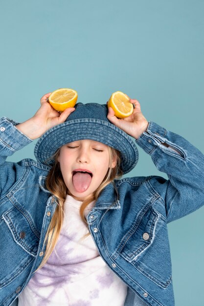 スライスしたレモンを頭に抱え、舌を出さない女の子の肖像画