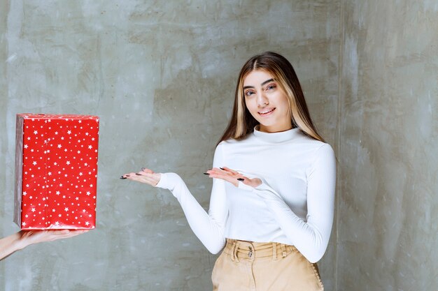 石の上に分離された現在のボックスの近くに立っている女の子モデルの肖像画