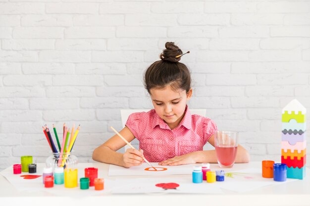 Portrait of a girl painting on white paper with paintbrush