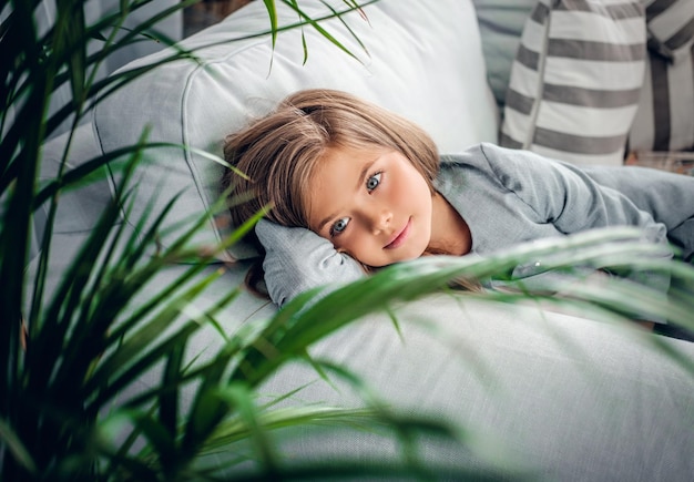 Free photo portrait of a girl posing on a sofa in a living room with green plants.