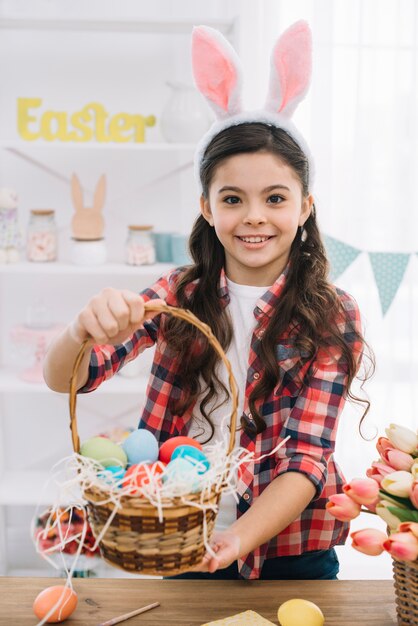 Портрет девушки, показывая корзину, полную красочных пасхальных яиц
