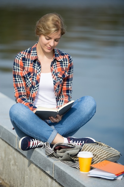 Portrait of a girl sitting turkish at the bridge reading