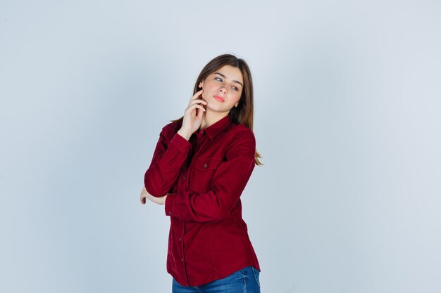 Portrait of Girl touching cheek with fingers, looking away in casual shirt and looking pensive