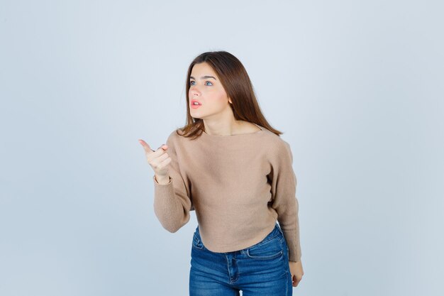 Portrait of girl warning with finger in sweater, jeans and looking angry