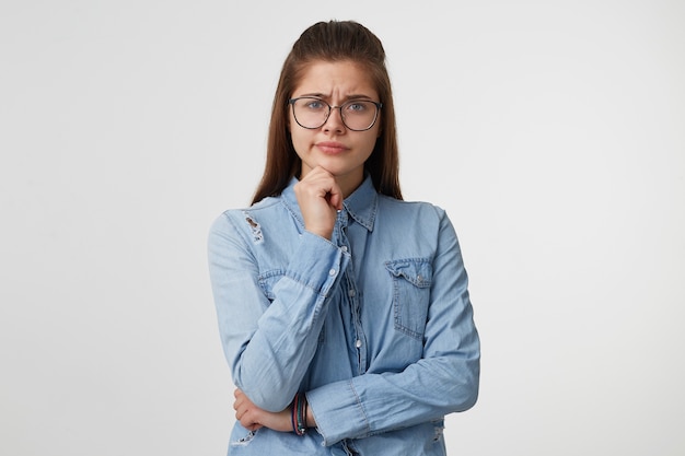 Portrait of a girl with eyeglasses and a arm on waist an other on chin on white