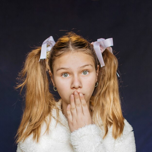 Portrait of a girl with hand on mouth