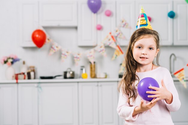 Портрет девушки с фиолетовым воздушным шаром, стоя на кухне