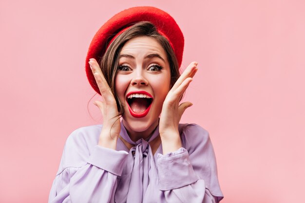 Portrait of girl with red lips and green eyes. Lady in beret screams with happiness.