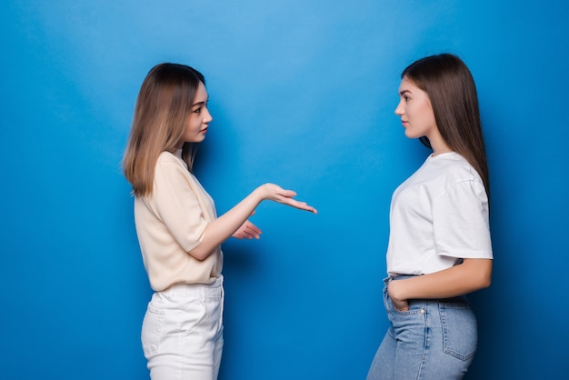 Portrait of girls talking spending time isolated on blue wall