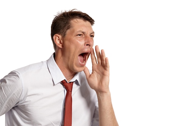 Portrait of a good-looking brunet fellow with brown eyes, wearing in a white shirt and a red tie. He is acting like calling someone while posing in a studio isolated over a white background. Concept o