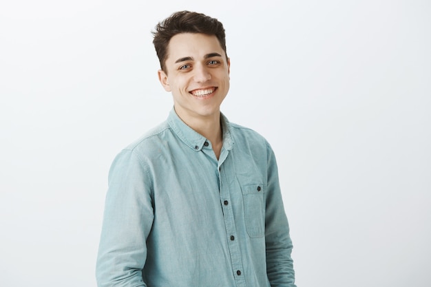 Portrait of good-looking friendly brother standing half-turned and smiling broadly