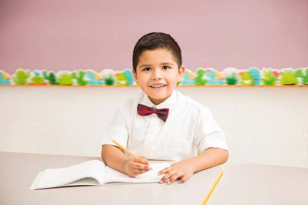 Portrait of a good looking Hispanic kid wearing a uniform and enjoying classes at preschool