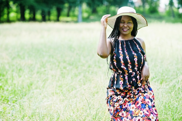Portrait of gorgeous african american woman 20s in summer hat posing at green grass in park
