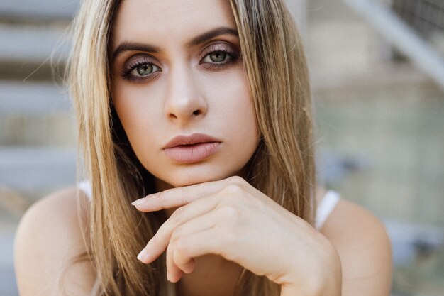 Portrait of gorgeous blonde woman sitting on the concrete footsteps