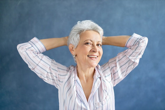 Free photo portrait of gorgeous middle aged woman in stylish striped pajamas stretching body after awakening early in the morning