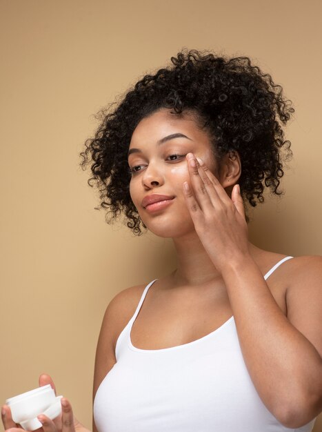 Portrait of a gorgeous woman applying moisturizer on her face