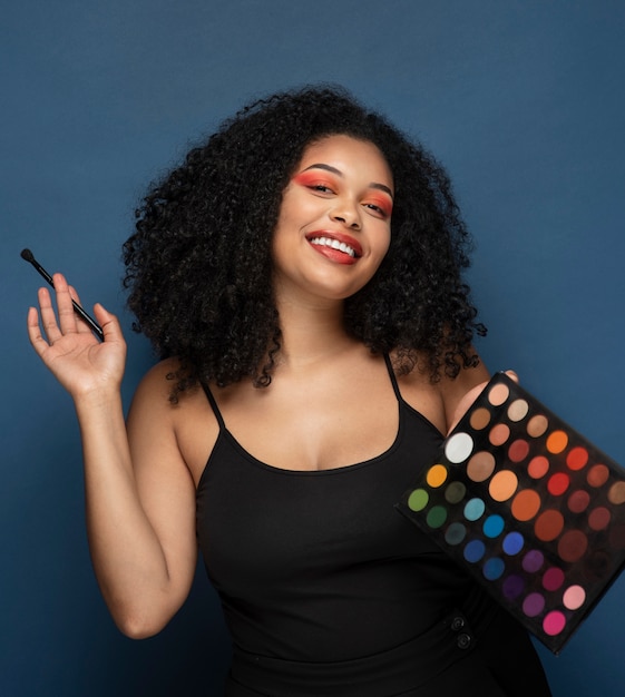 Portrait of a gorgeous woman holding an eyeshadow palette