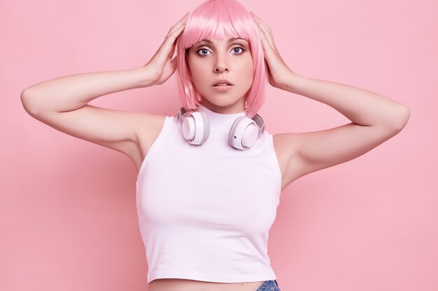 Portrait of gorgeous woman with pink hair enjoys the music in headphones