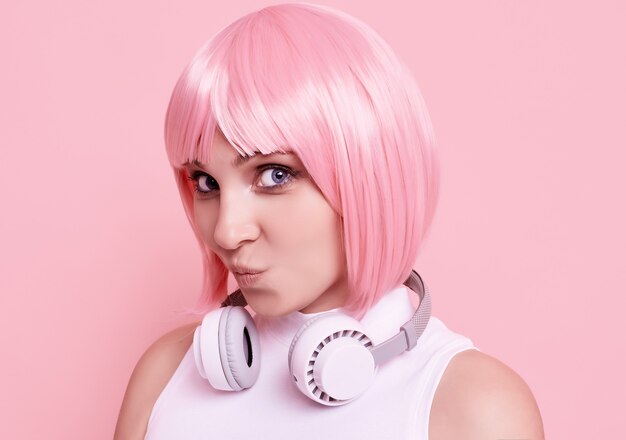 분홍색 머리를 가진 화려한 여자의 초상화는 헤드폰에서 음악을 즐긴다