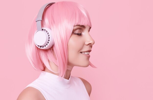 분홍색 머리를 가진 화려한 여자의 초상화는 헤드폰에서 음악을 즐긴다