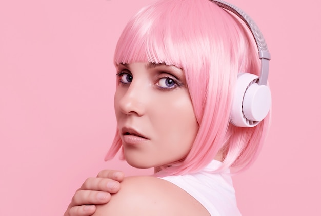 Portrait of gorgeous woman with pink hair enjoys the music in headphones