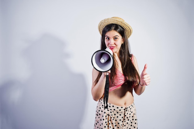 Foto gratuita ritratto di una splendida ragazza in costume da bagno e cappello parla nel megafono in studio