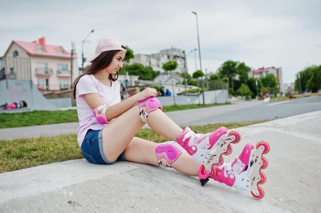 Free photo portrait of a gorgeous young woman in casual clothes and cap sitting on the ground next to the lake