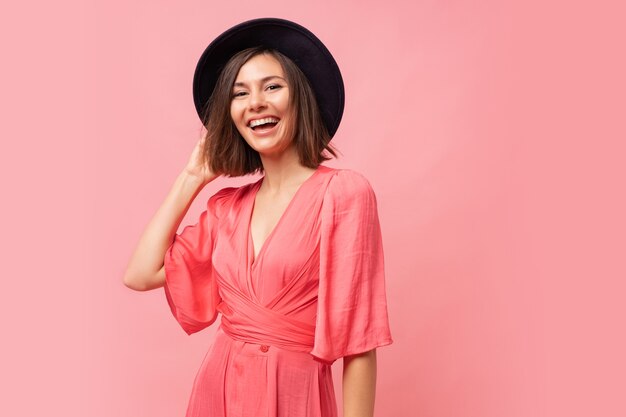 портрет изящной улыбающейся брюнетки в розовом платье