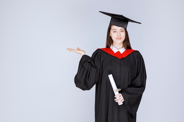 Портрет аспиранта в платье с дипломом и стоя. Фото высокого качества