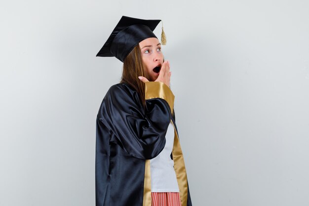 Portrait of graduate woman holding hand on open mouth while yawning in casual clothes, uniform and looking dreamy front view